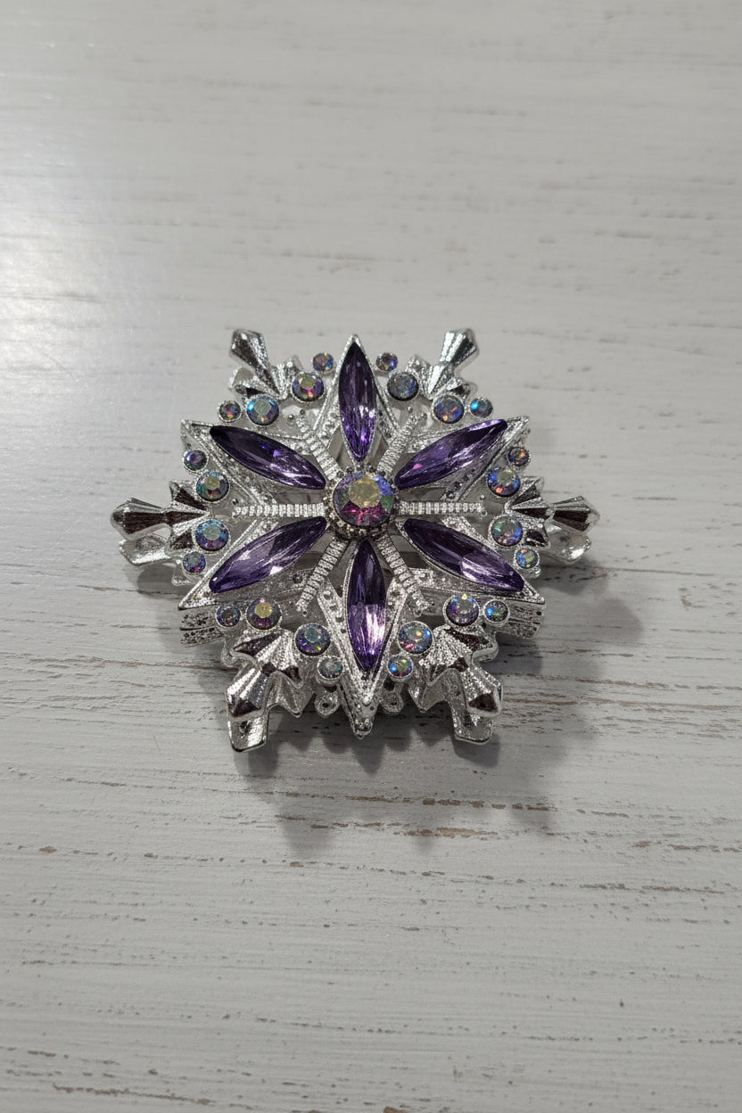 A snowflake-shaped silver bead decorated with purple marquise-cut crystals and small iridescent rhinestones.