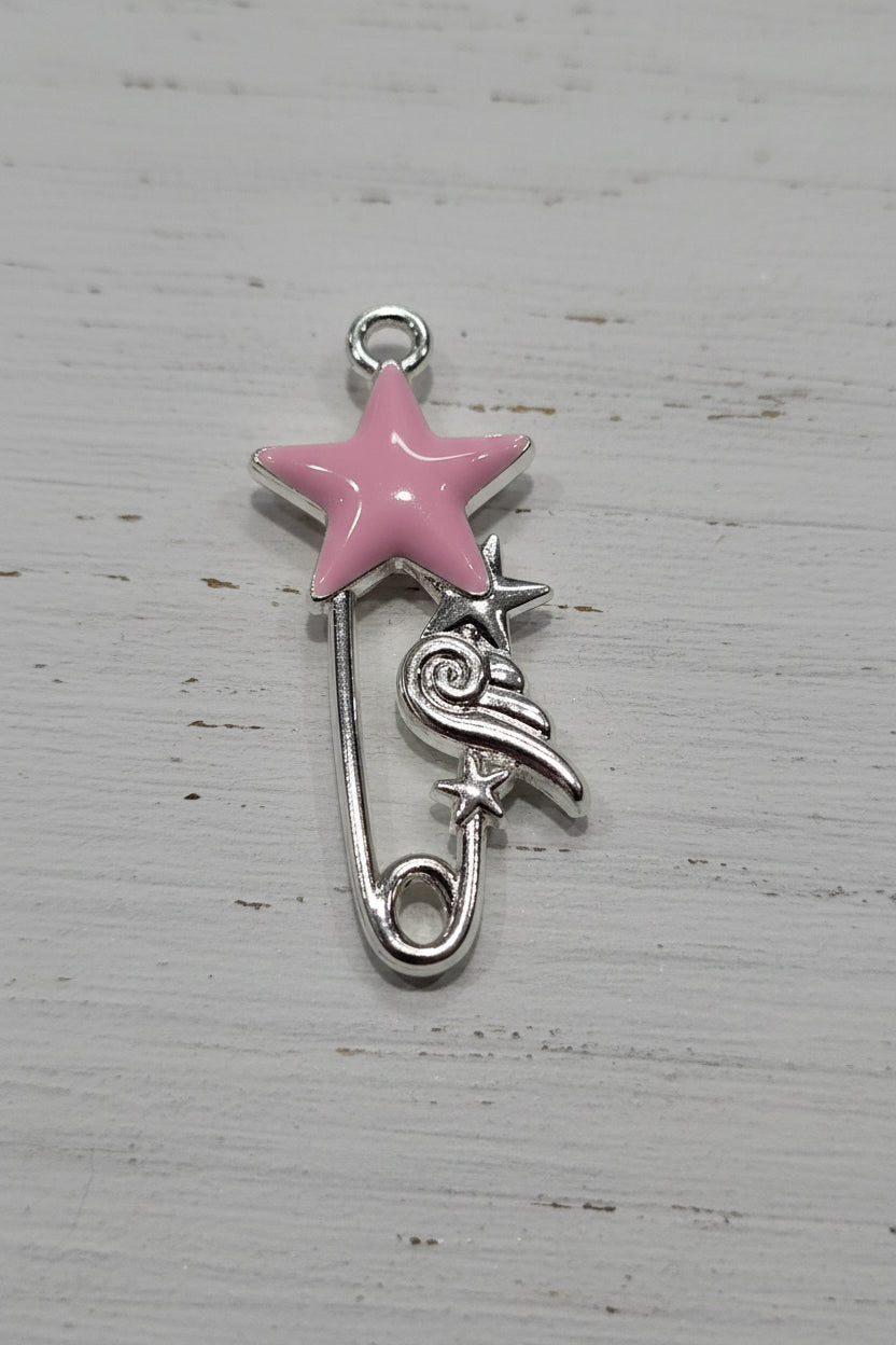A silver safety pin charm featuring a pink enamel star on top and a small silver bird with a star accent.