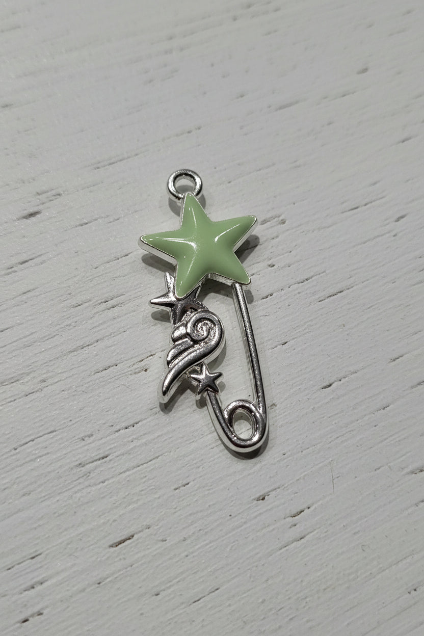 A silver-toned safety pin charm designed as a shooting star, featuring a light green enamel star.