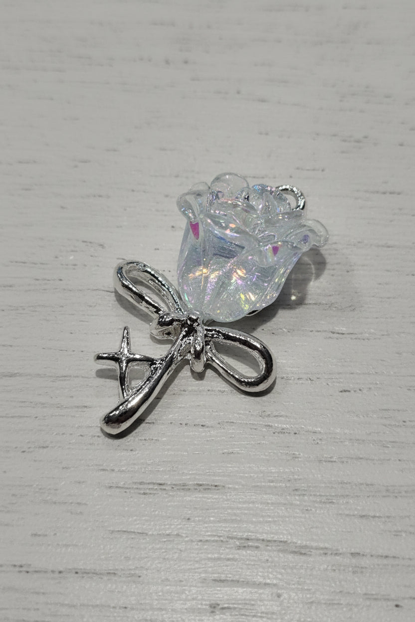 A small jewelry charm featuring a silver-toned bow with a clear, iridescent, flower-shape