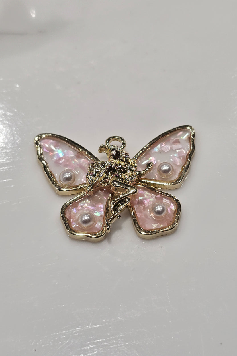 A butterfly-shaped charm featuring iridescent pink wings with pearl-like accents and a gold-tone body and borders.