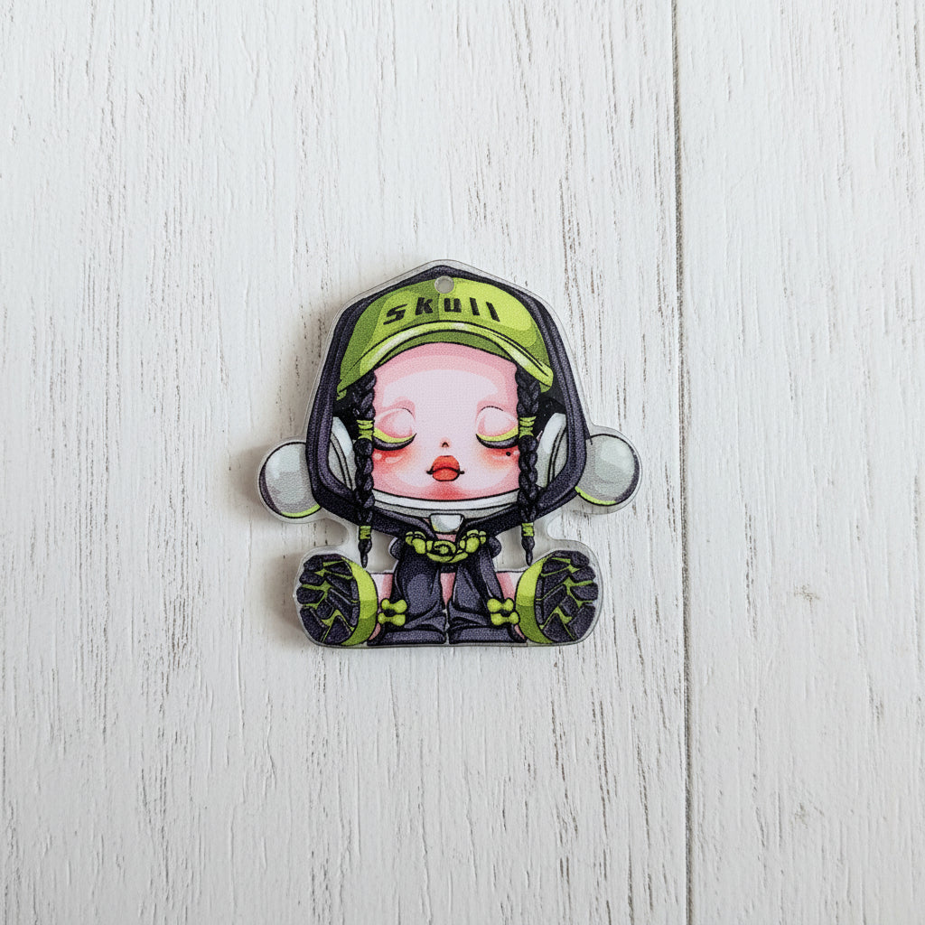 A small illustrated acrylic bead with a cartoon character wearing a green cap that says 'skull' and dark clothing.