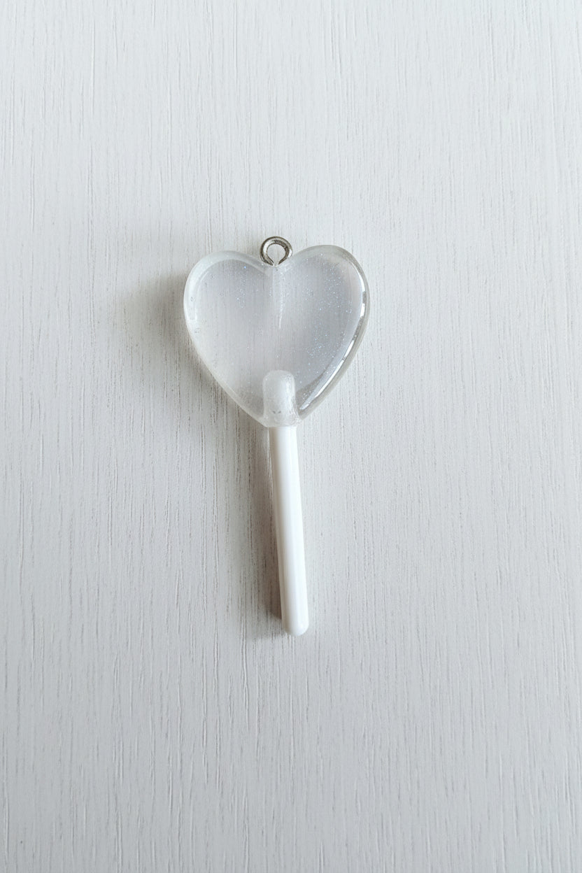 A heart-shaped translucent lollipop pendant with a white stick.