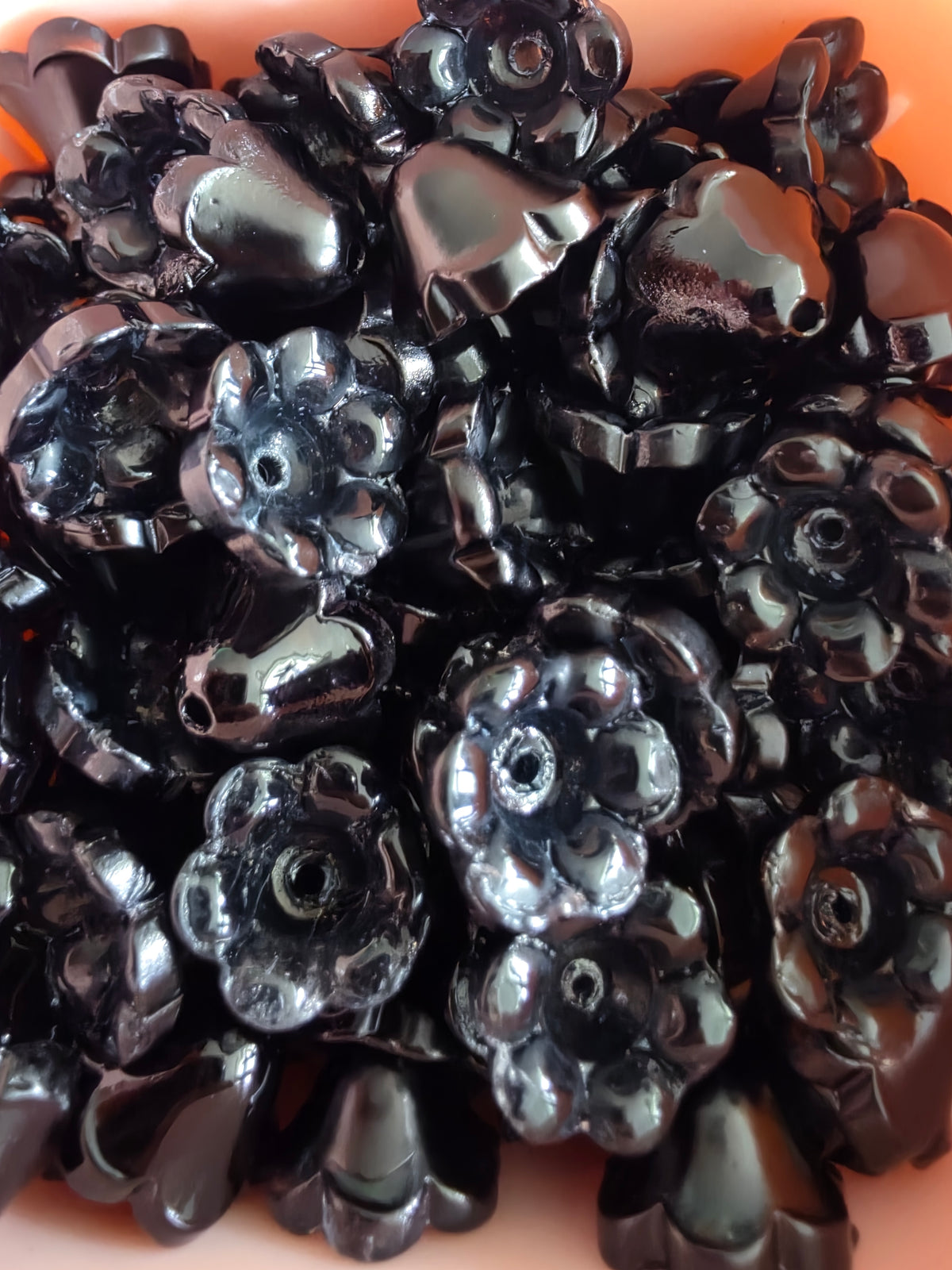 A pile of glossy black glass flowers.