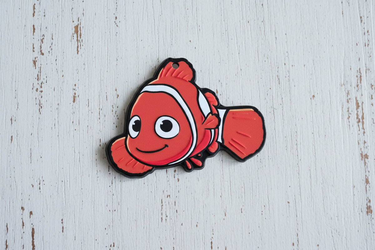 A red and white clownfish-shaped acrylic bead with black outline details.