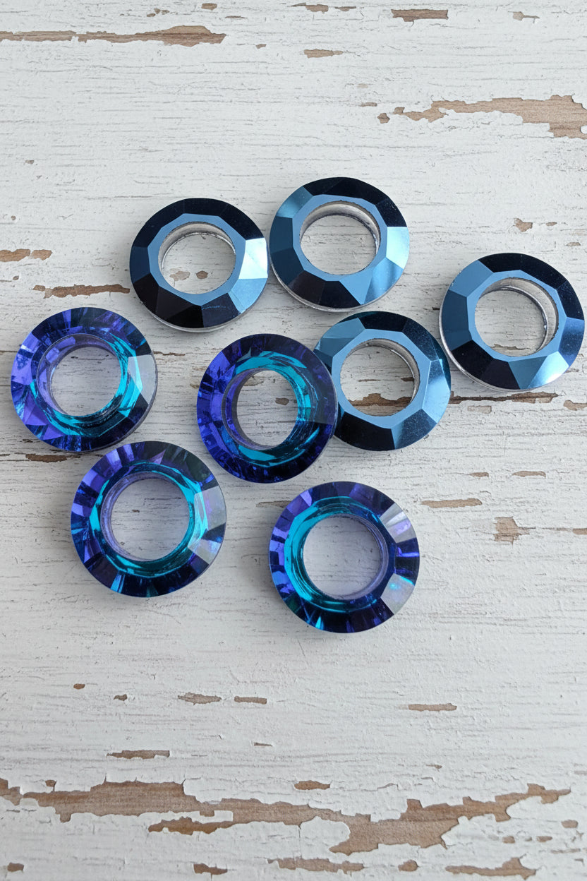Six faceted circular glass beads in shades of blue, purple, and black.