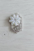 A silver-toned filigree jewellery connector featuring a large iridescent white flower.