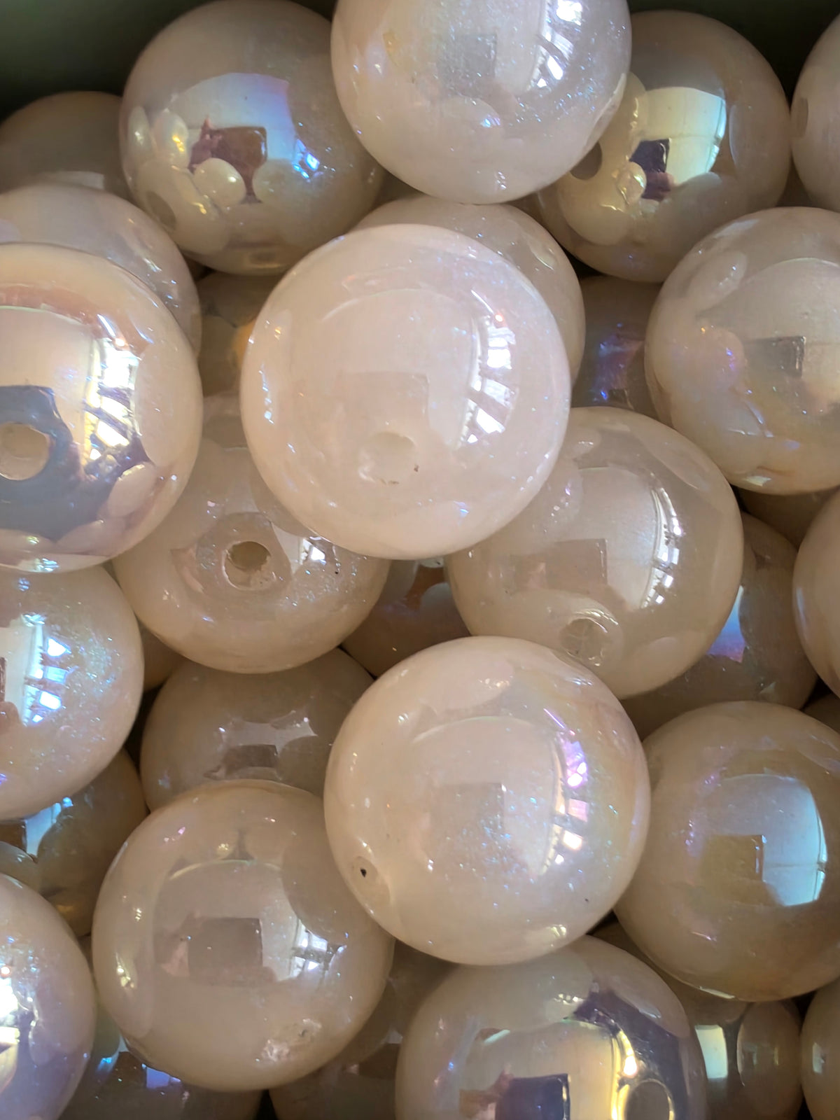 A close-up pile of round, iridescent white or cream color, showing subtle rainbow reflections.