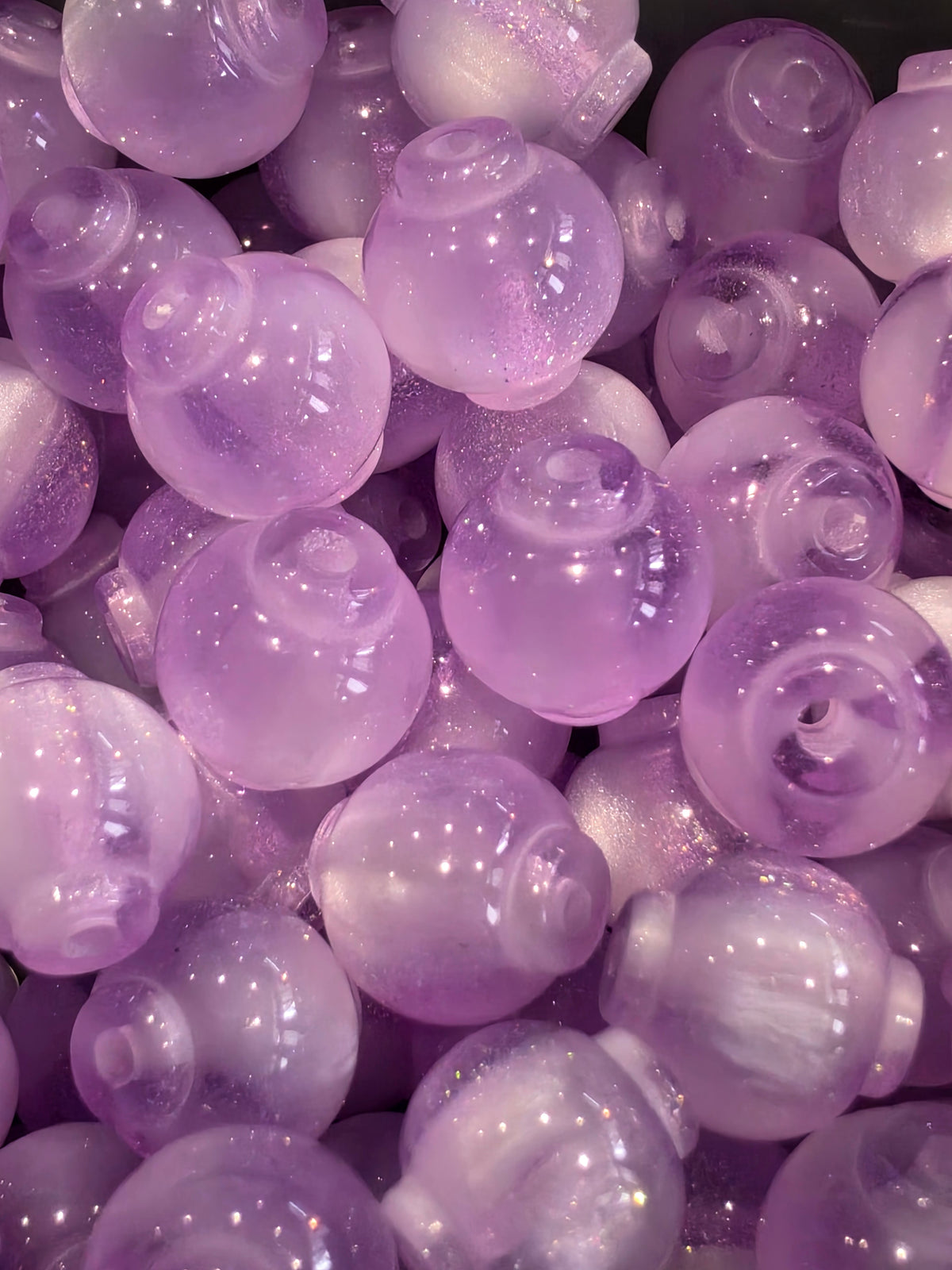 A close-up pile of 12mm lavender purple beads with a glittery finish.