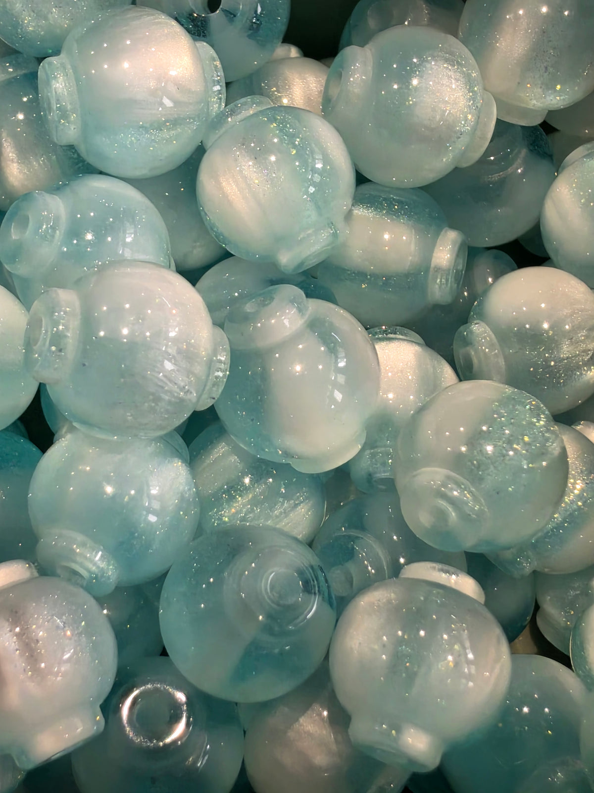 A close-up pile of 12mm blue beads with a glittery finish.
