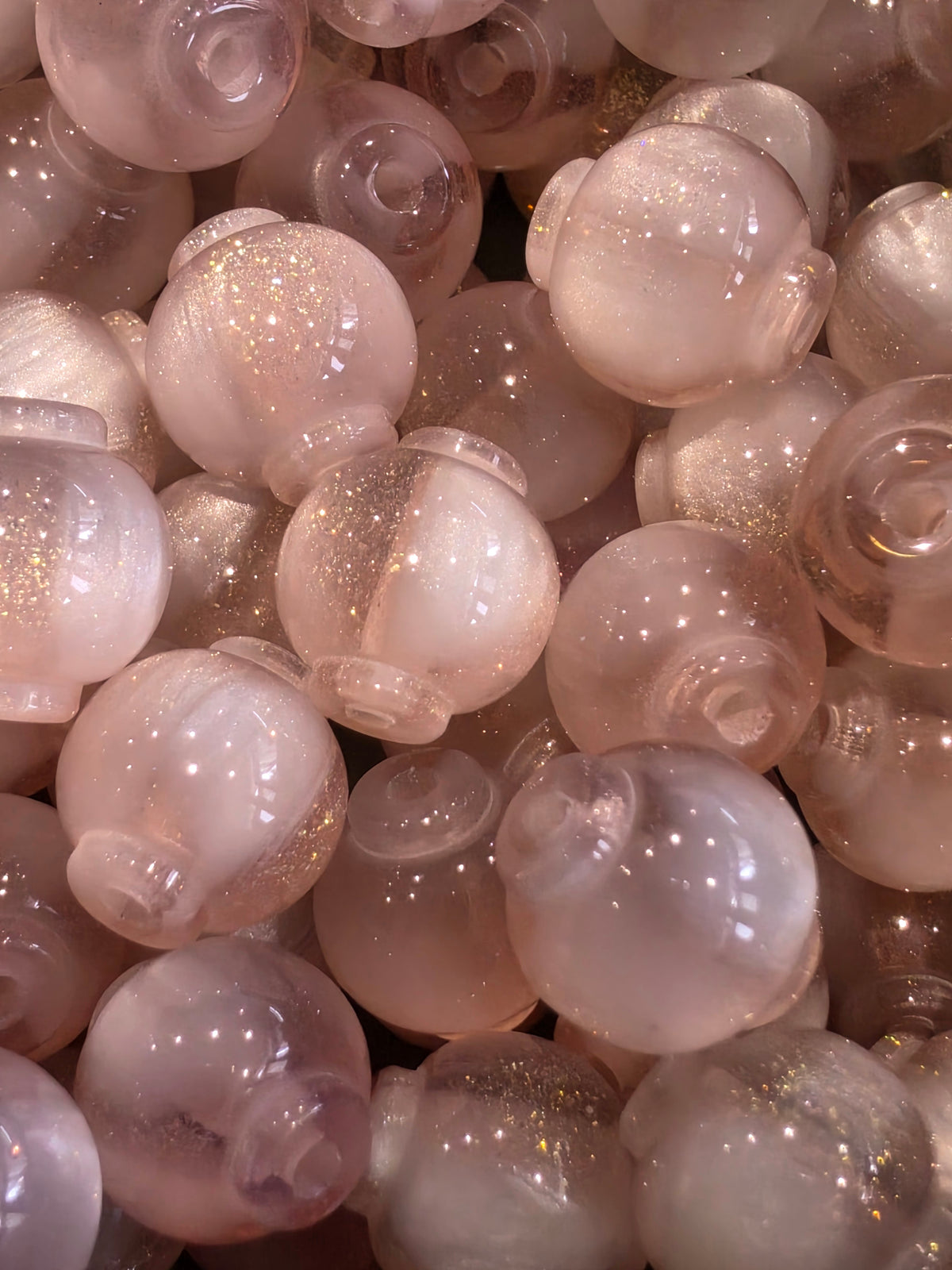 A close-up pile of 12mm pink beads with a glittery finish.