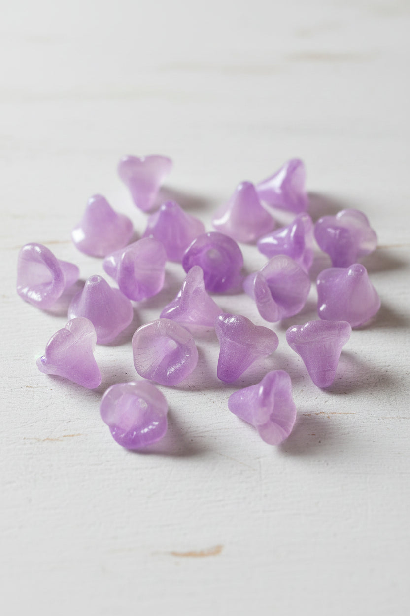 A close-up of several translucent purple and white glass flower-shaped beads.