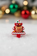 A small Christmas-themed decorative bead shaped like a tree with a reindeer face on the front, in red, white, tan, and small multicolor accents.