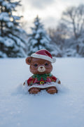 A small teddy bear bead wearing a red Santa hat with white trim and a red Santa outfit with a green bow tie.