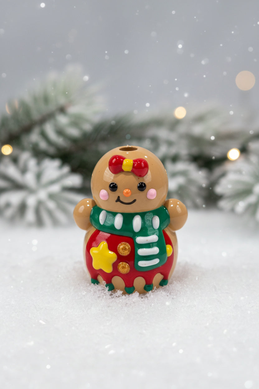 A small gingerbread bead  decorated with a red bow, green scarf, red body, and yellow and white details.