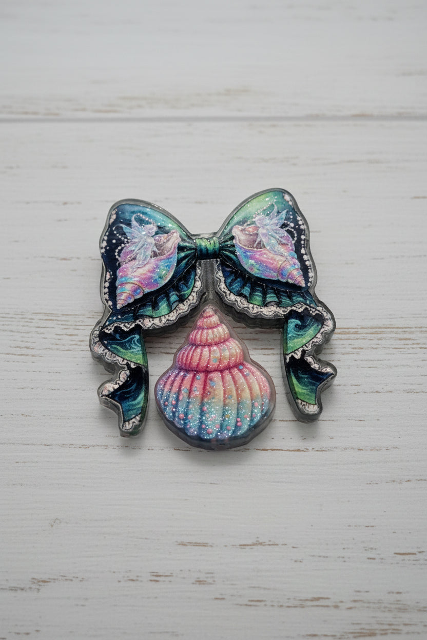 A decorative acrylic bow and bead set featuring iridescent pastel pink, blue, and green 