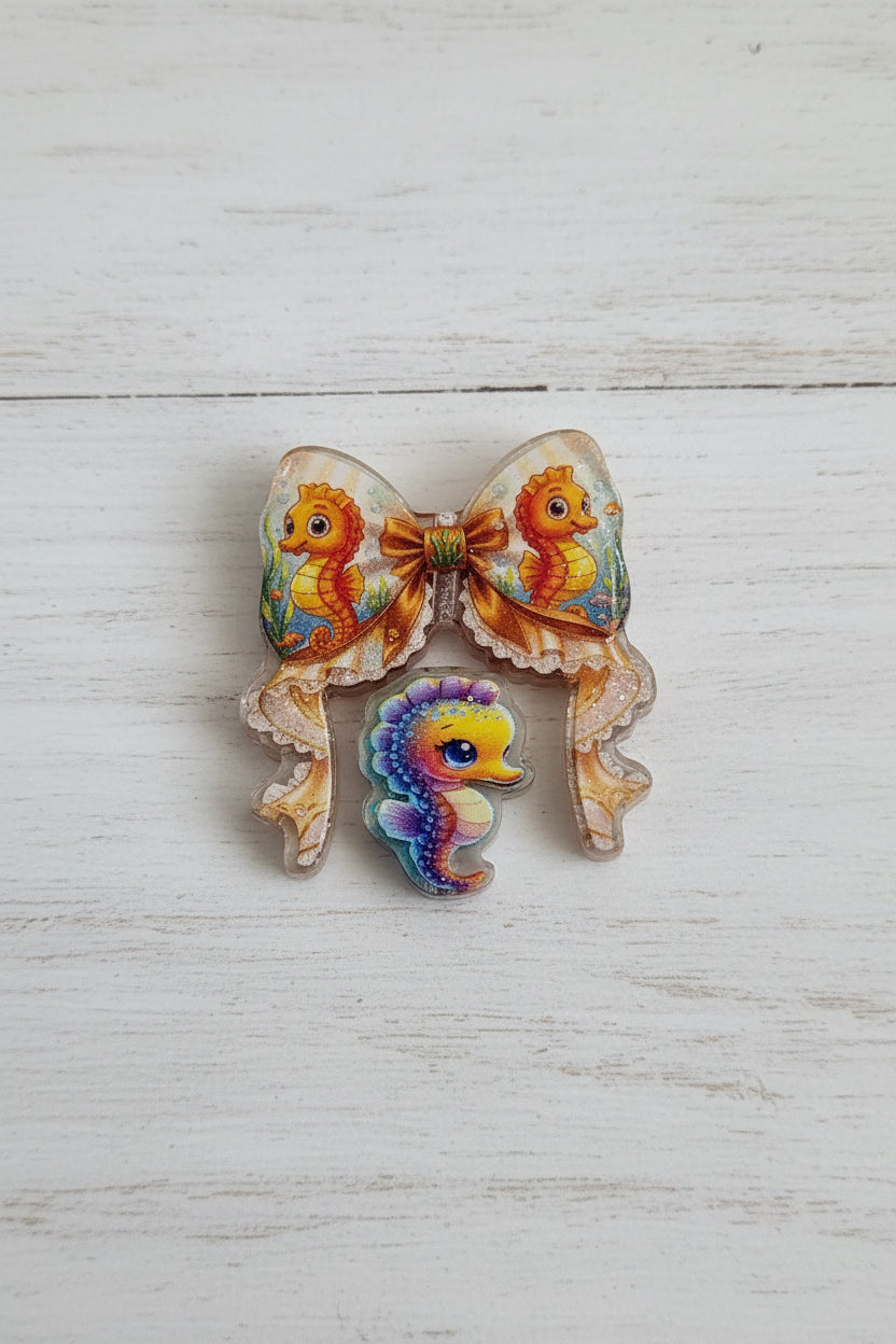 An acrylic bow and bead set with beige edges and colorful seahorse illustrations, featuring a smaller multicolored seahorse bead