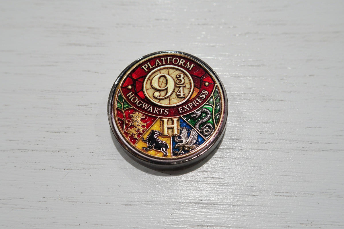 A round acrylic bead with colourful lion crest details and the Hogwarts 'H' logo.