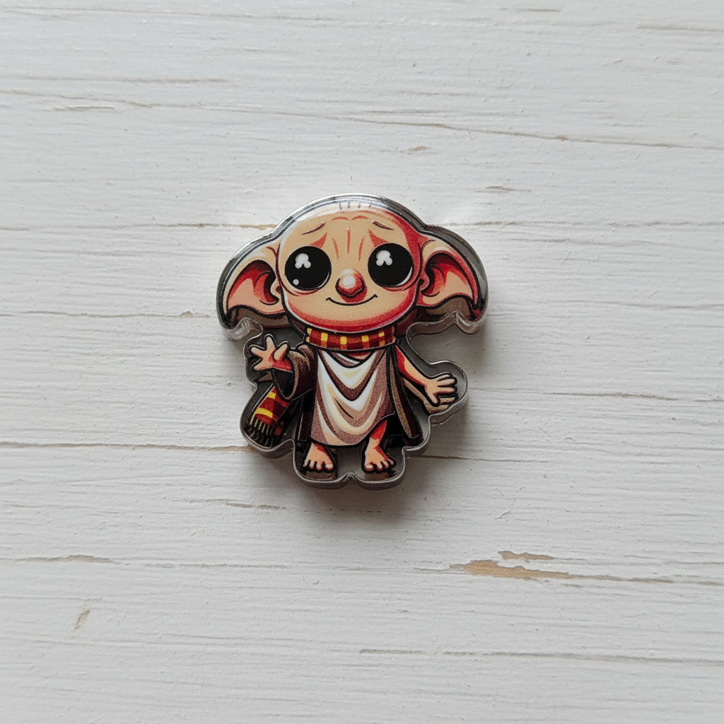A small acrylic bead shaped like a cartoon creature with large black eyes, pointed ears, and a beige robe.