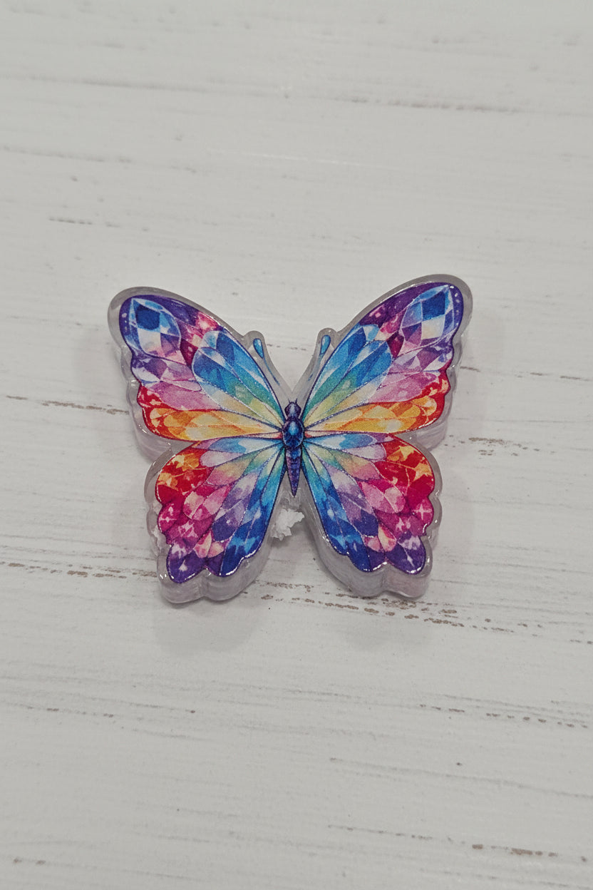 A butterfly-shaped accessory with a vibrant, multicolored gemstone-like pattern in shades of blue, purple, pink, and orange.