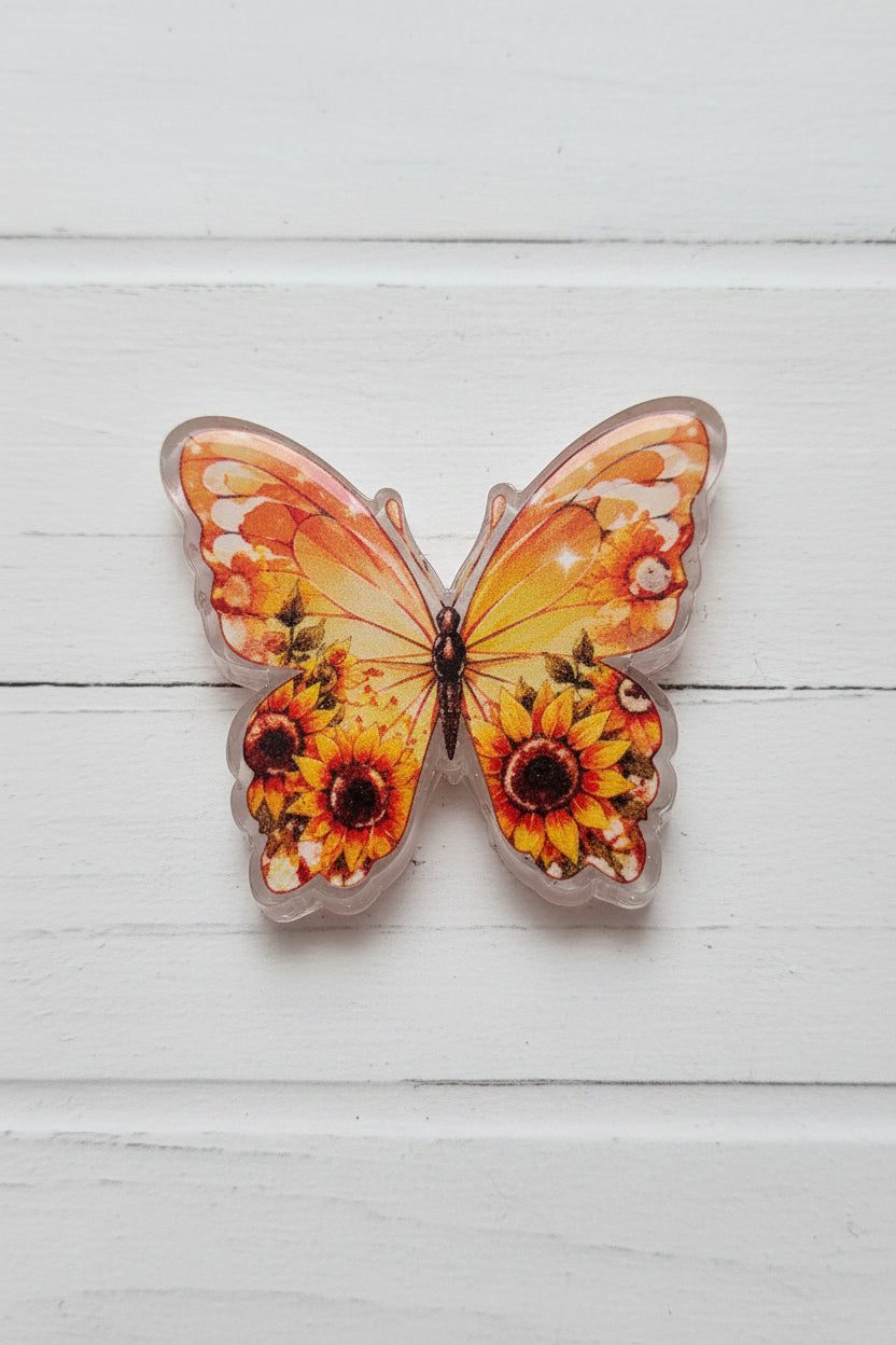 A butterfly-shaped acrylic bead featuring printed orange and yellow sunflower designs.