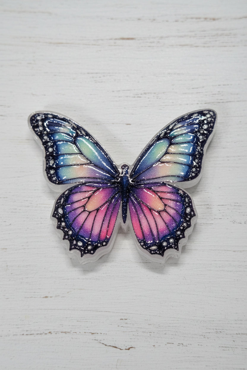A butterfly-shaped accessory with iridescent pastel wings in pink, purple, blue, and green, outlined in black.
