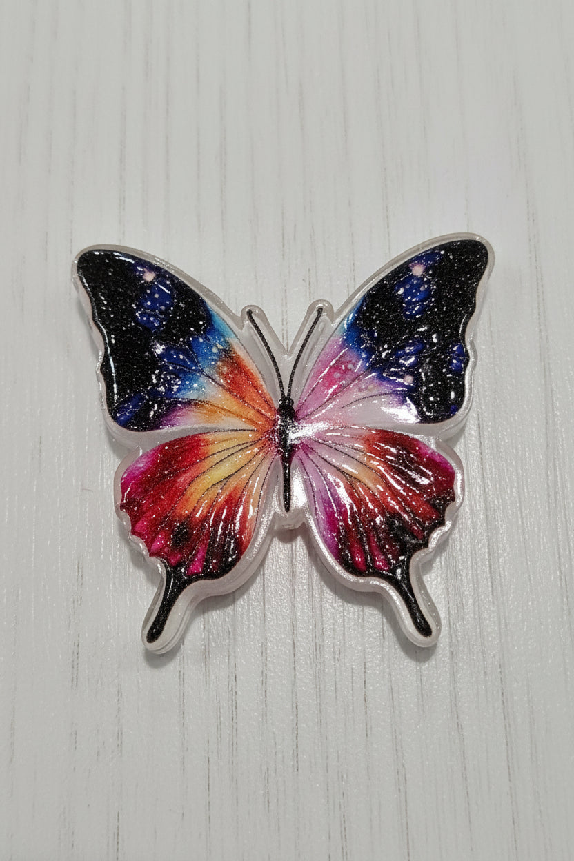 A butterfly-shaped acrylic bead with a vibrant galaxy design, featuring black, blue, pink, red, and orange wing patterns.