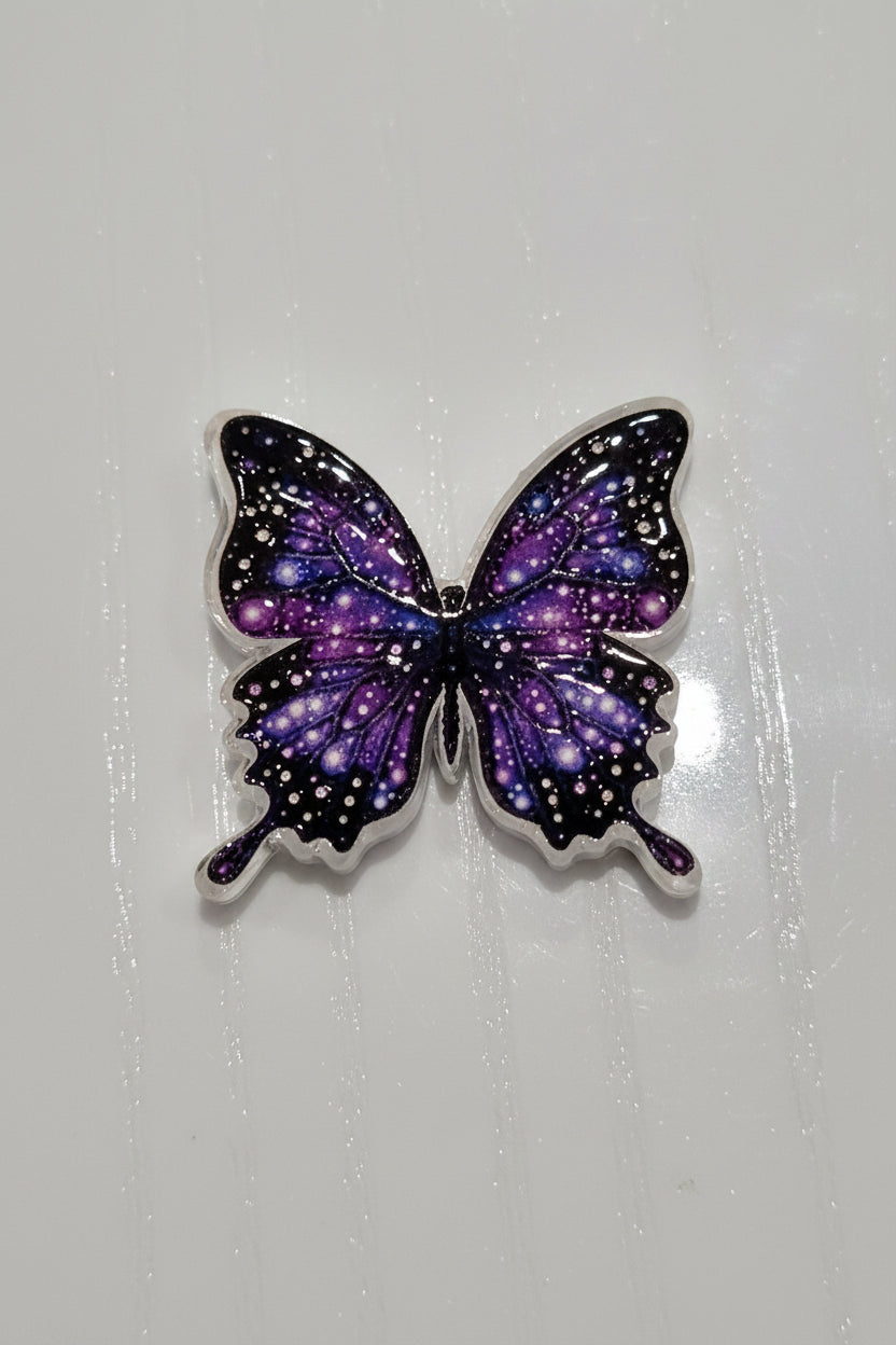 A butterfly-shaped acrylic bead with a galaxy print in purple, blue, and black.
