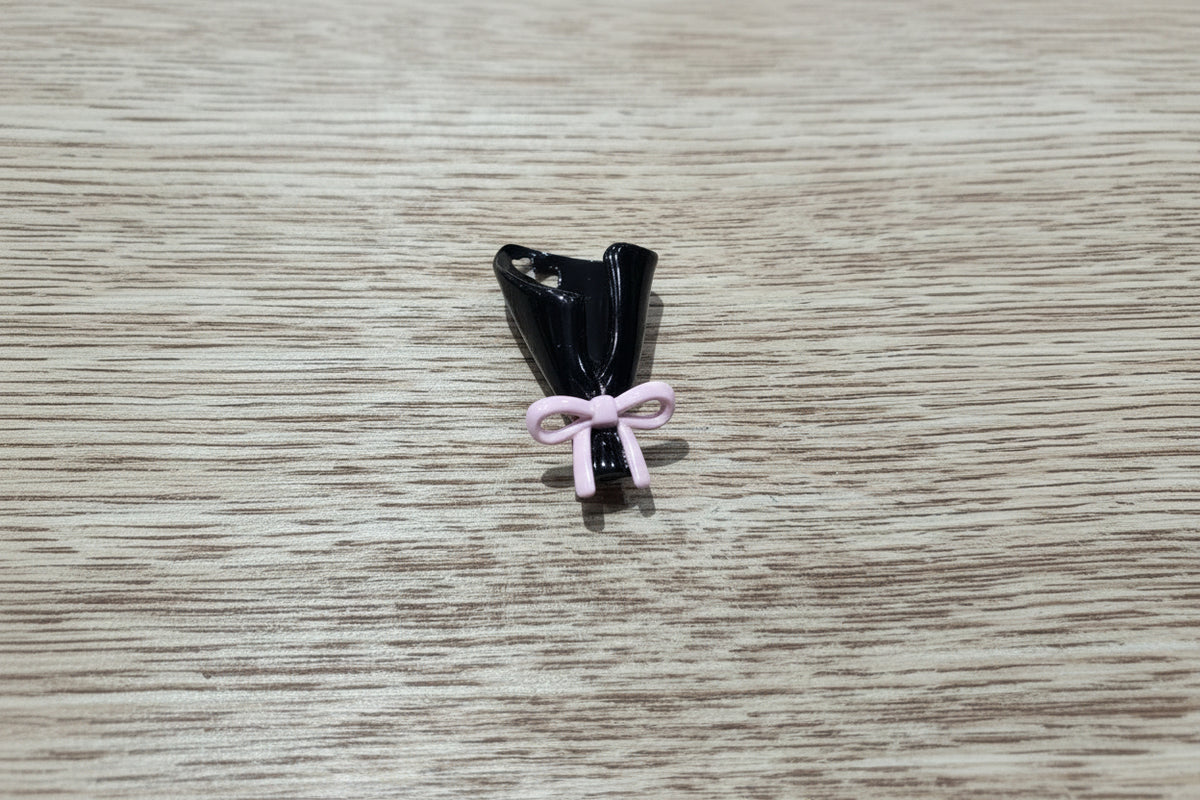 A small black bouquet shaped bead with a light pink bow tied around the base.