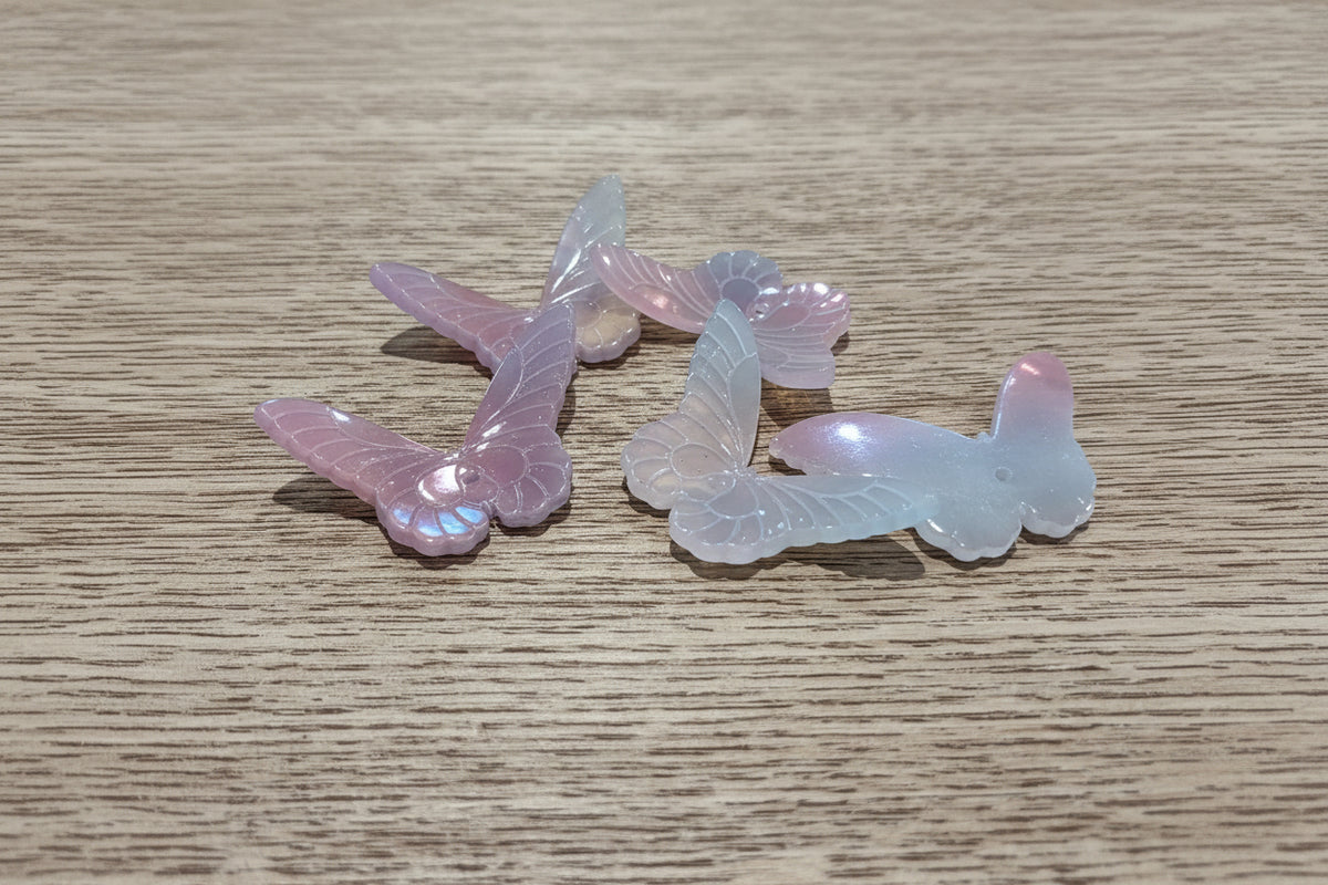 iridescent butterfly-shaped beads with a pink, purple, and blue color-shifting sheen.