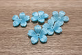 light blue flower beads with a glossy, textured finish.