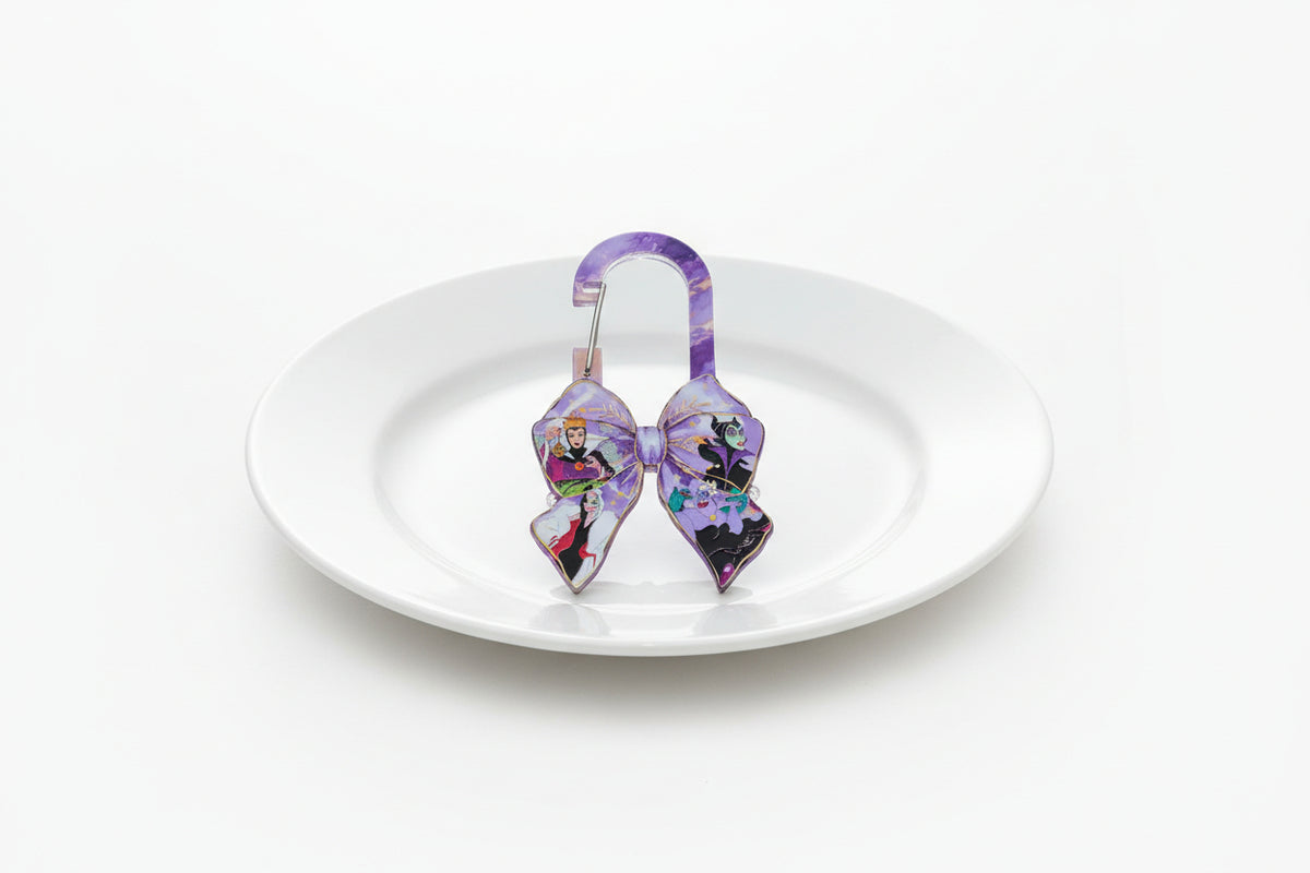 A purple bow-shaped keyring with a carabiner clip,  resting on a wooden surface.