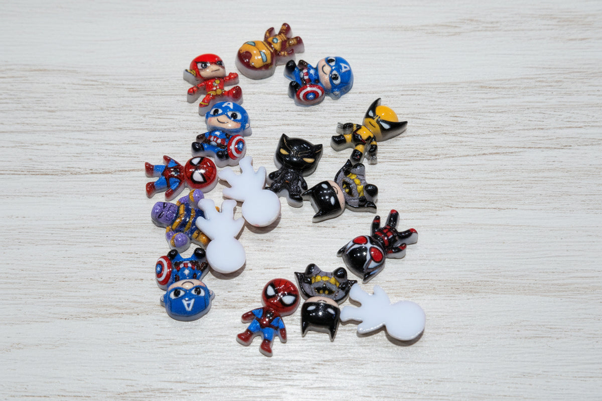 A collection of small, colorful cartoon character charms and white ghost-shaped beads scattered on a light brown wood grain surface.