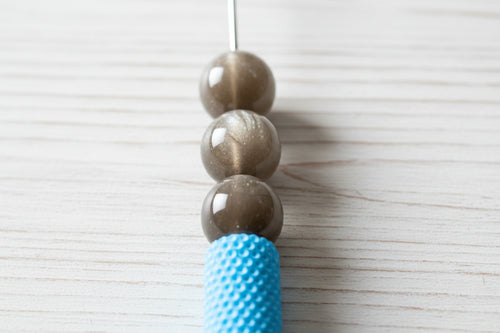 A close-up of glossy brown-grey round resin beads.