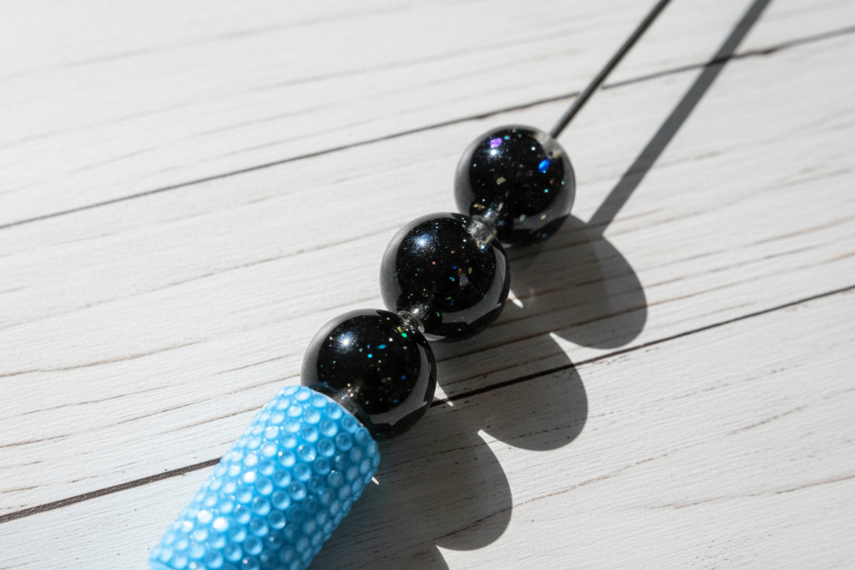 A close-up glossy resin black beads with embedded iridescent glitter.