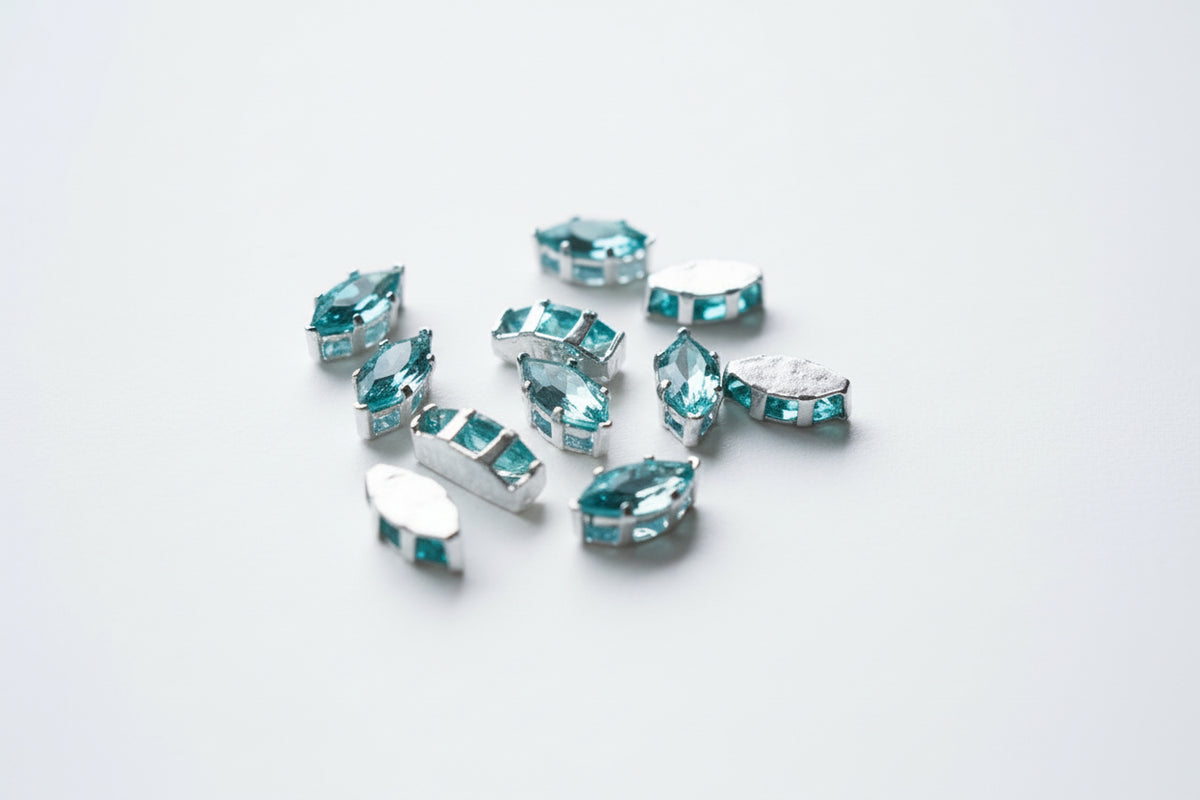 Turquoise zircons with silver settings scattered on a light brown wood grain surface.