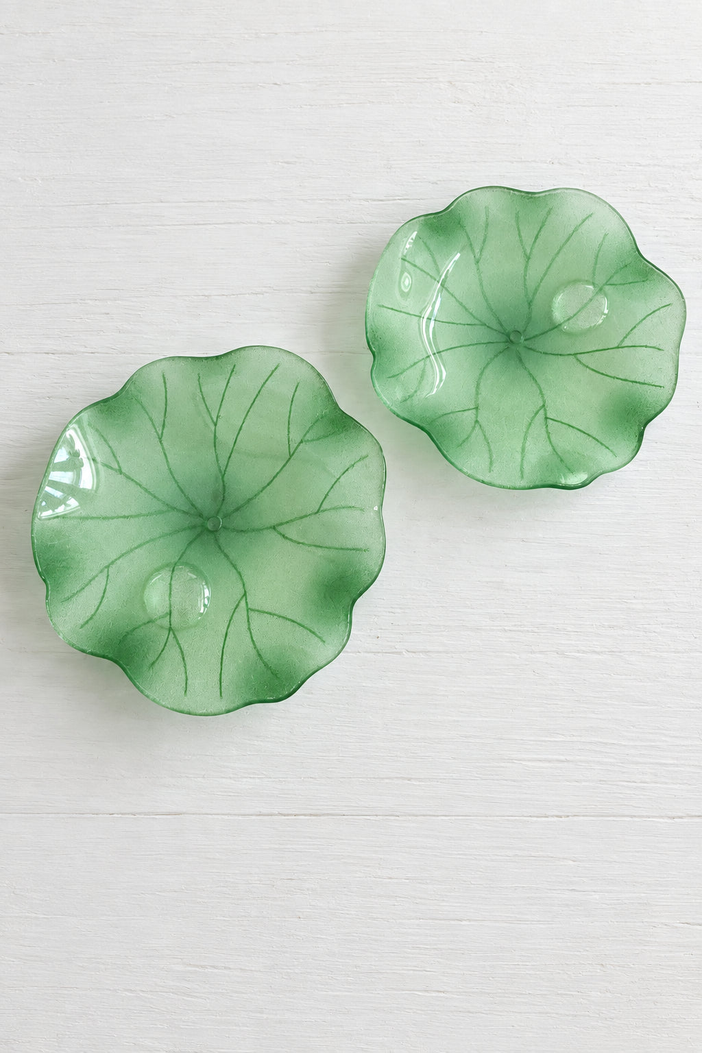 Acetate lily-pad beads with scalloped edges and embossed vein patterns, placed on a white surface.