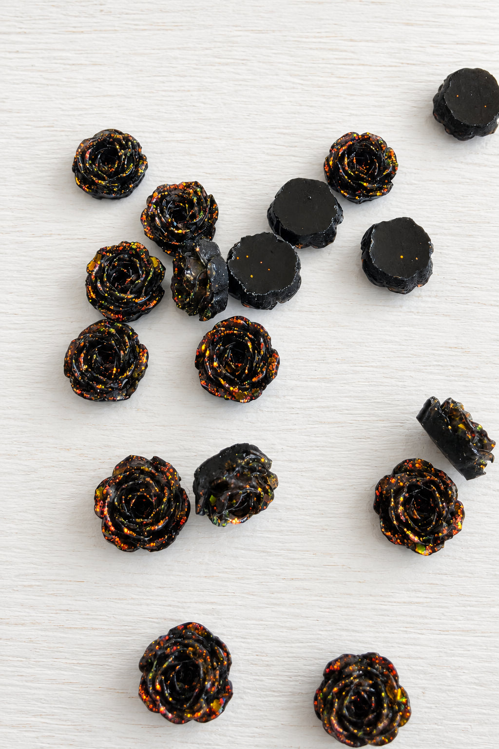 Several small dark brown rose-shaped items with glittery orange and gold speckles.
