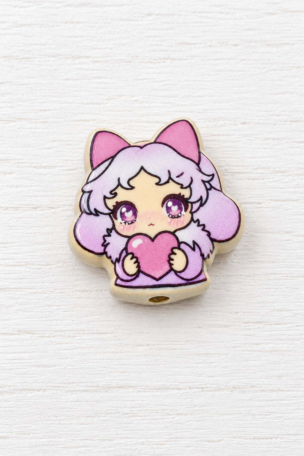 A small metal bead featuring an anime-style character with pink hair and a pink heart.