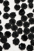 A dense arrangement of small black soft roses on a plain white background.