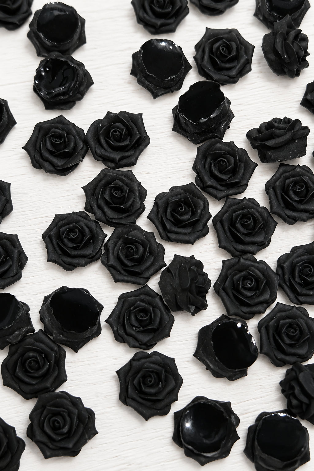 A dense arrangement of small black soft roses on a plain white background.