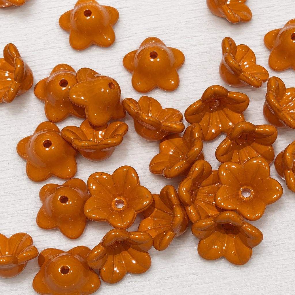 Acrylic brown flower-shaped beads with a central hole, scattered on a white surface.