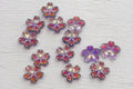 Small glass flower-shaped beads with iridescent purple petals.