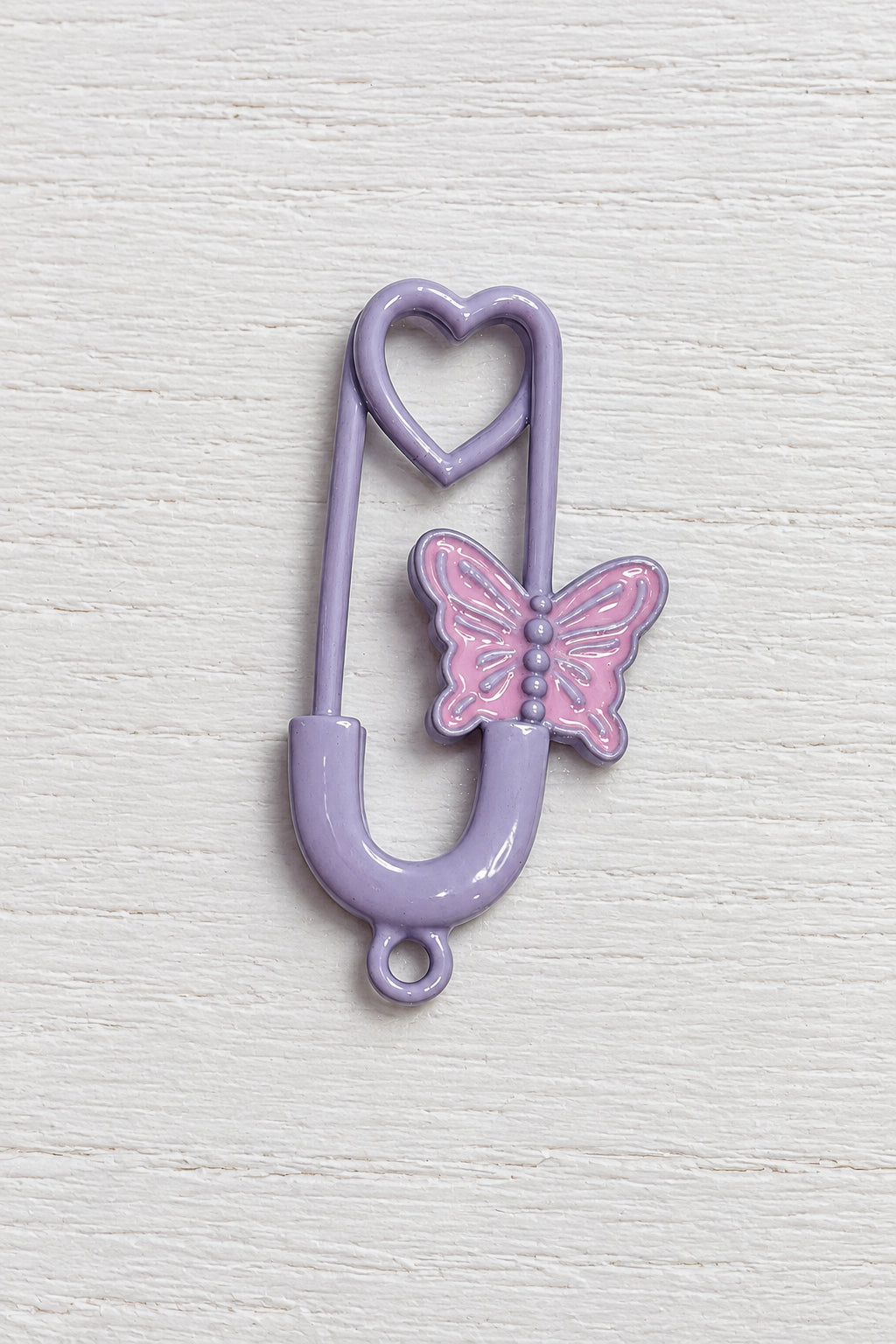 A lavender purple safety pin-shaped hair claw clip featuring a pink butterfly accent on the front.