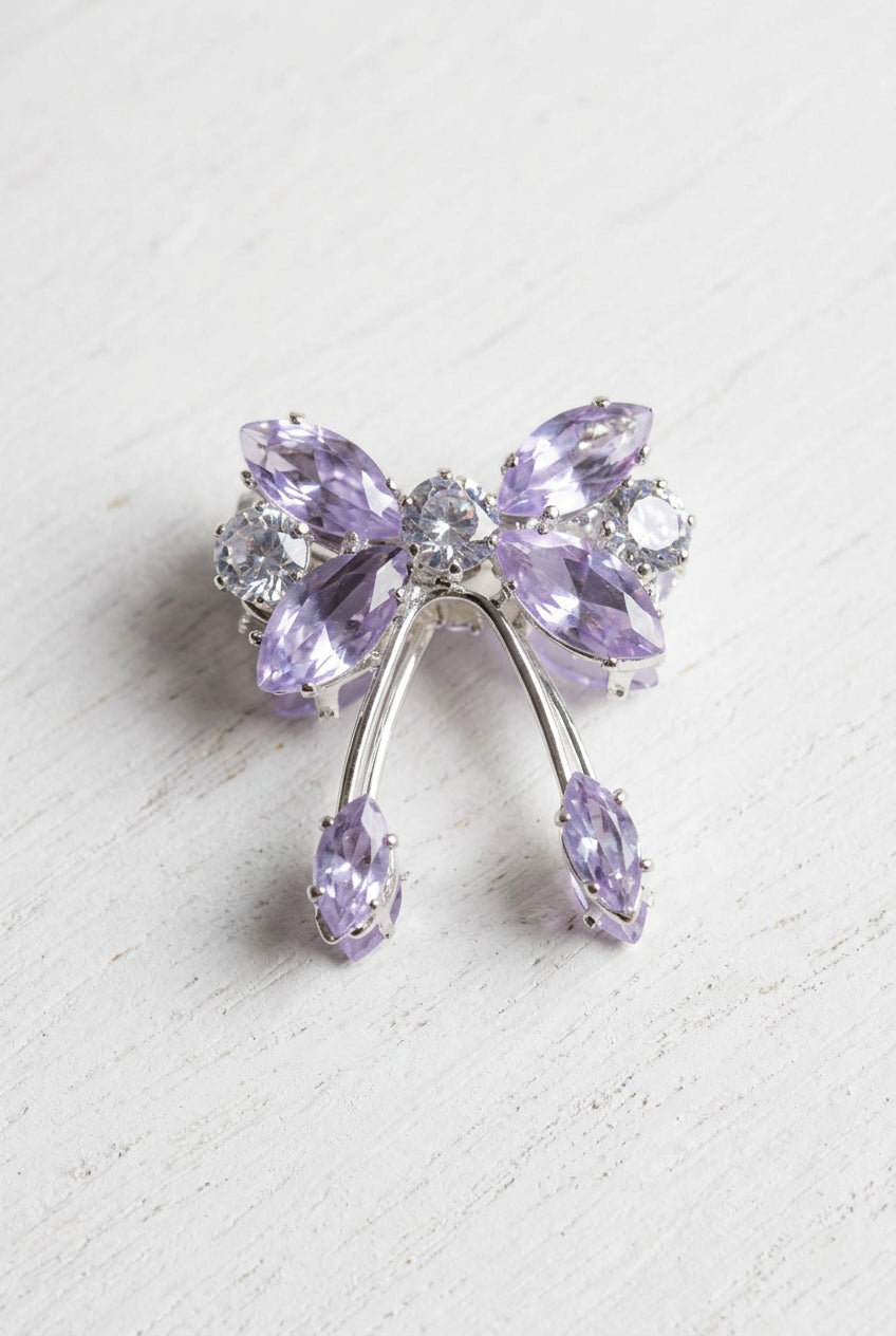 A silver-toned bow-shaped bead featuring faceted light purple/lavender and clear rhinestones, photographed on a plain white surface.