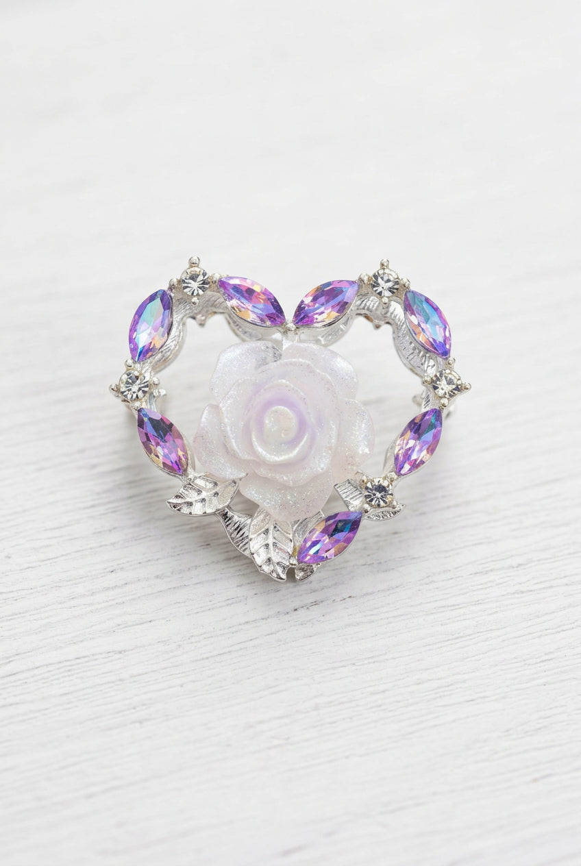 A heart-shaped bead featuring a central white rose with iridescent purple zircons