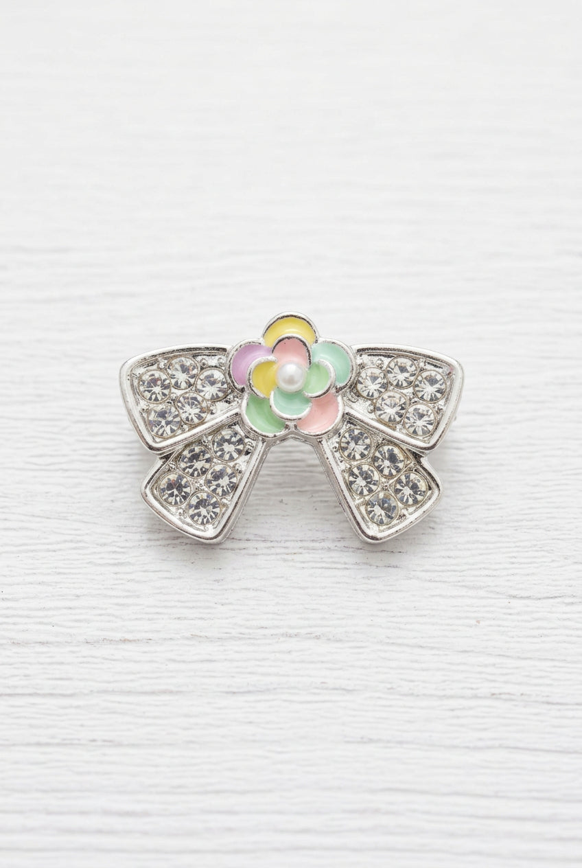 A silver bow-shaped bead with a colorful enamel flower centre.